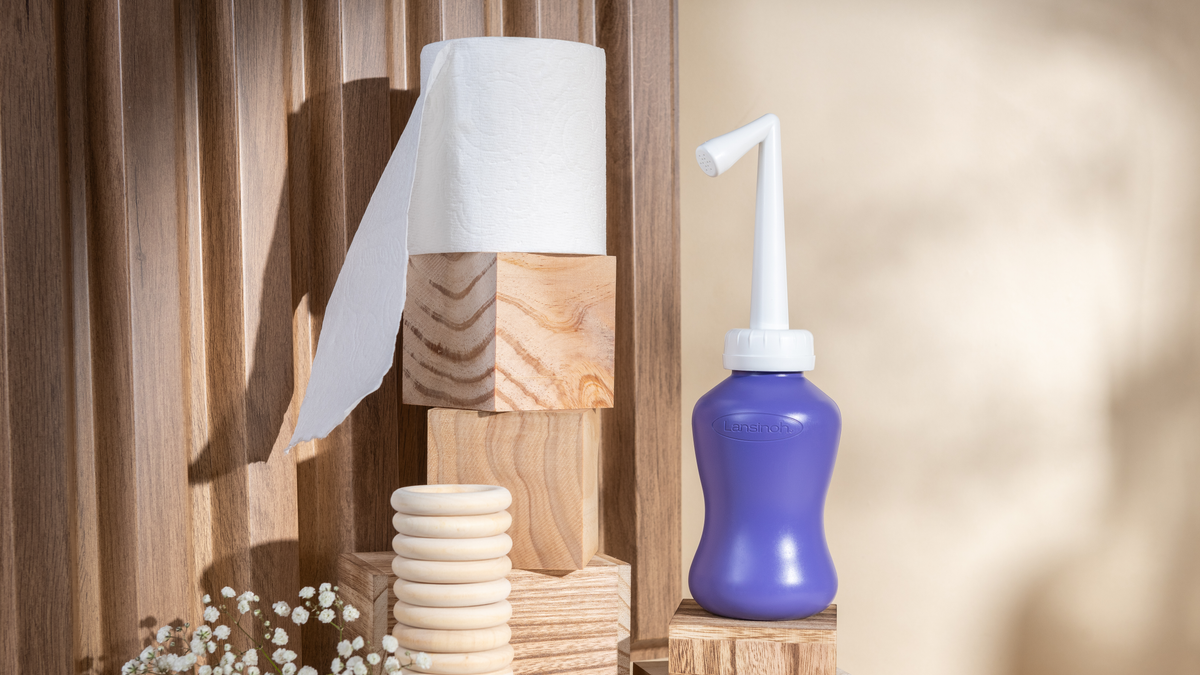 Wooden paper towel holder and a blue nasal aspirator on a wooden background.