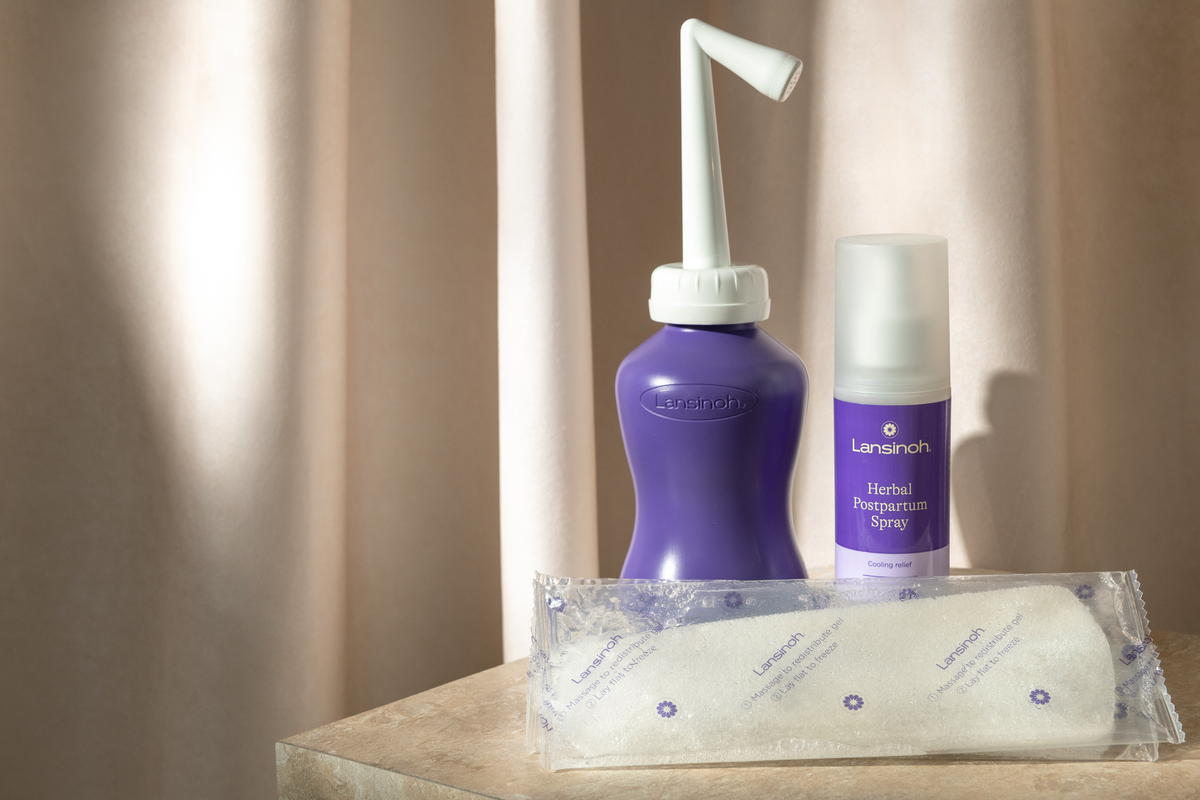 Lansinoh breastfeeding products displayed on a countertop with a draped beige backdrop.