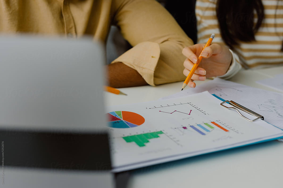 Two women discussing charts and graphs on paper at a table.