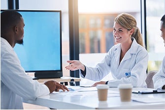 Two doctors sitting at a conference table having a discussion.