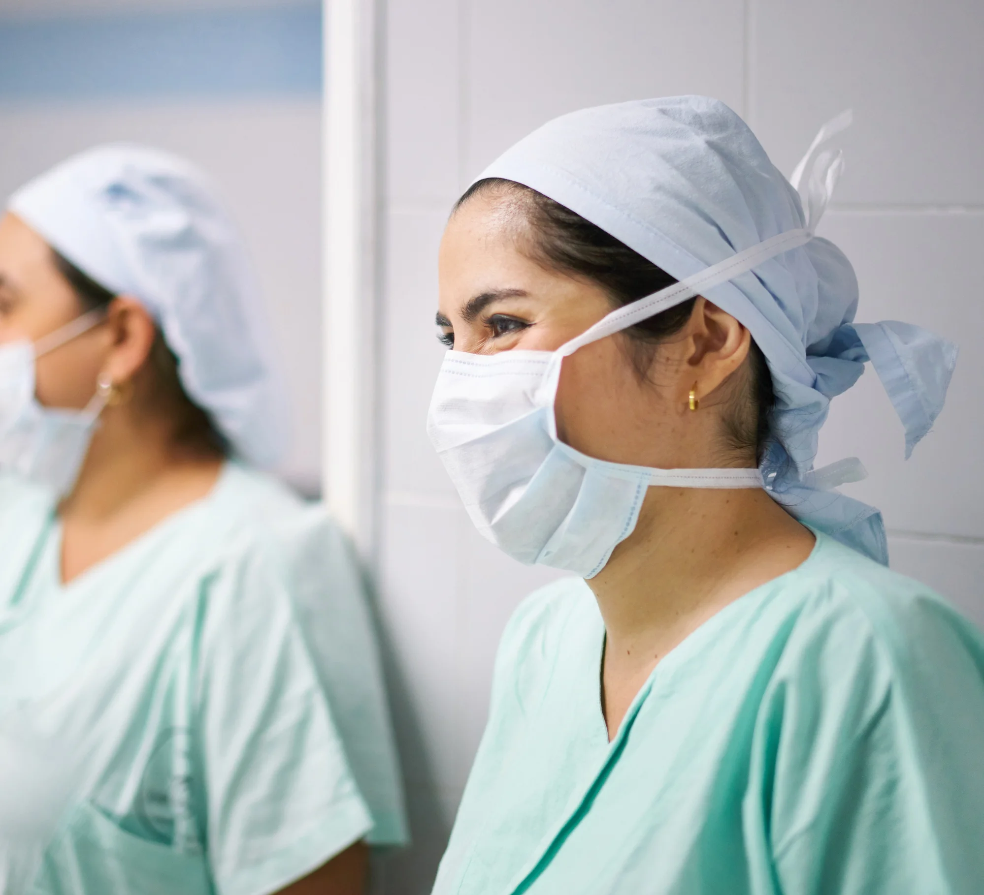 Two female nurses smiling while wearing surgical masks. 