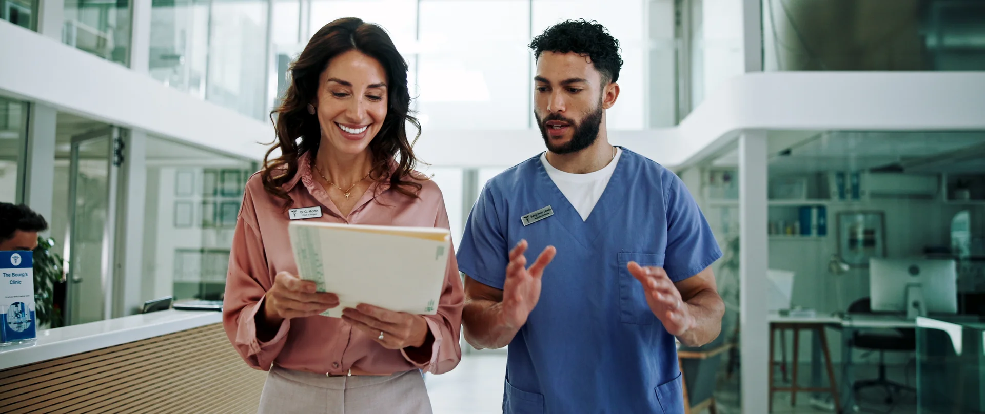 A man and a woman are looking at a tablet in a hospital hallway