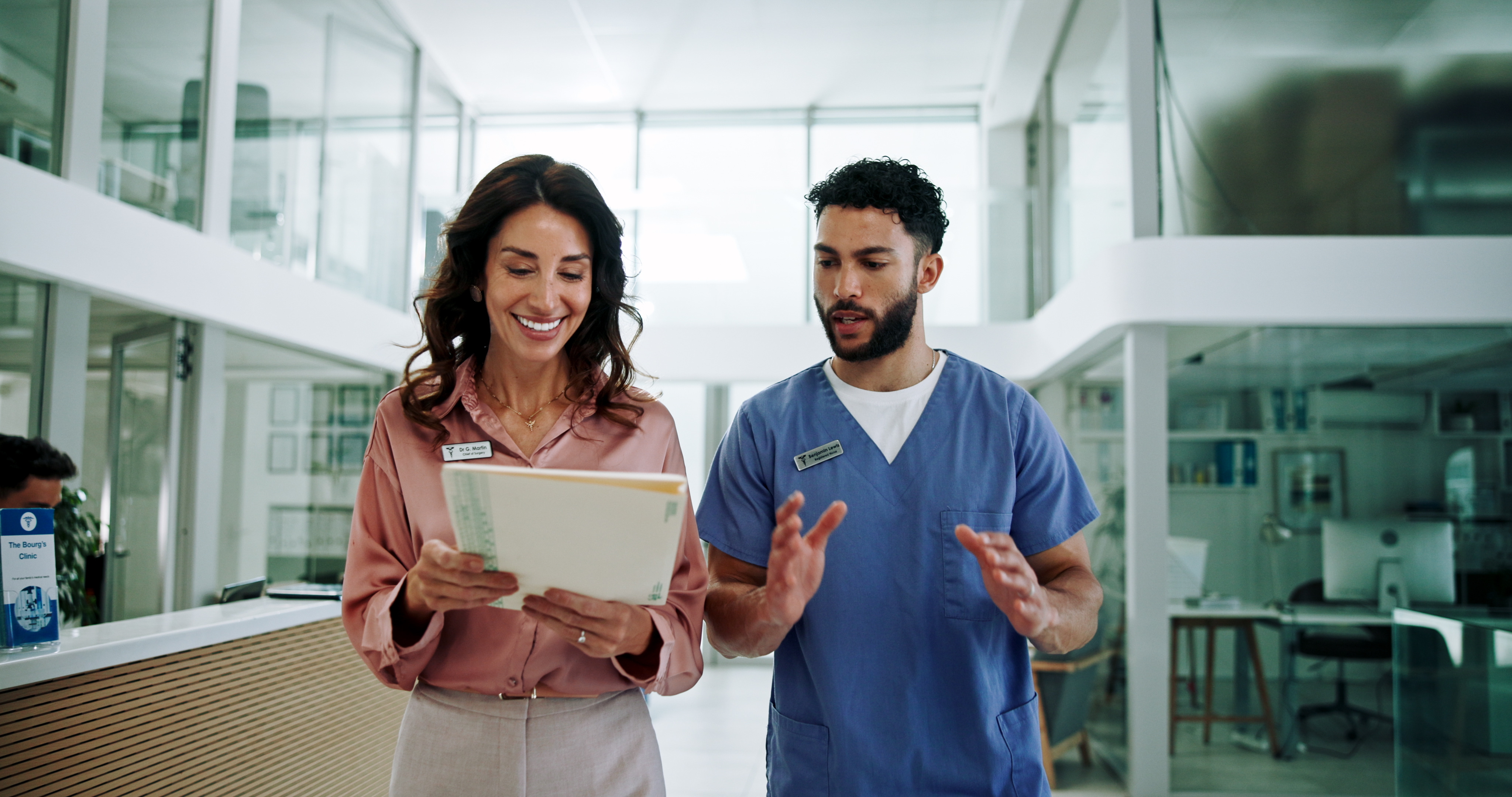A man and a woman are looking at a tablet in a hospital hallway