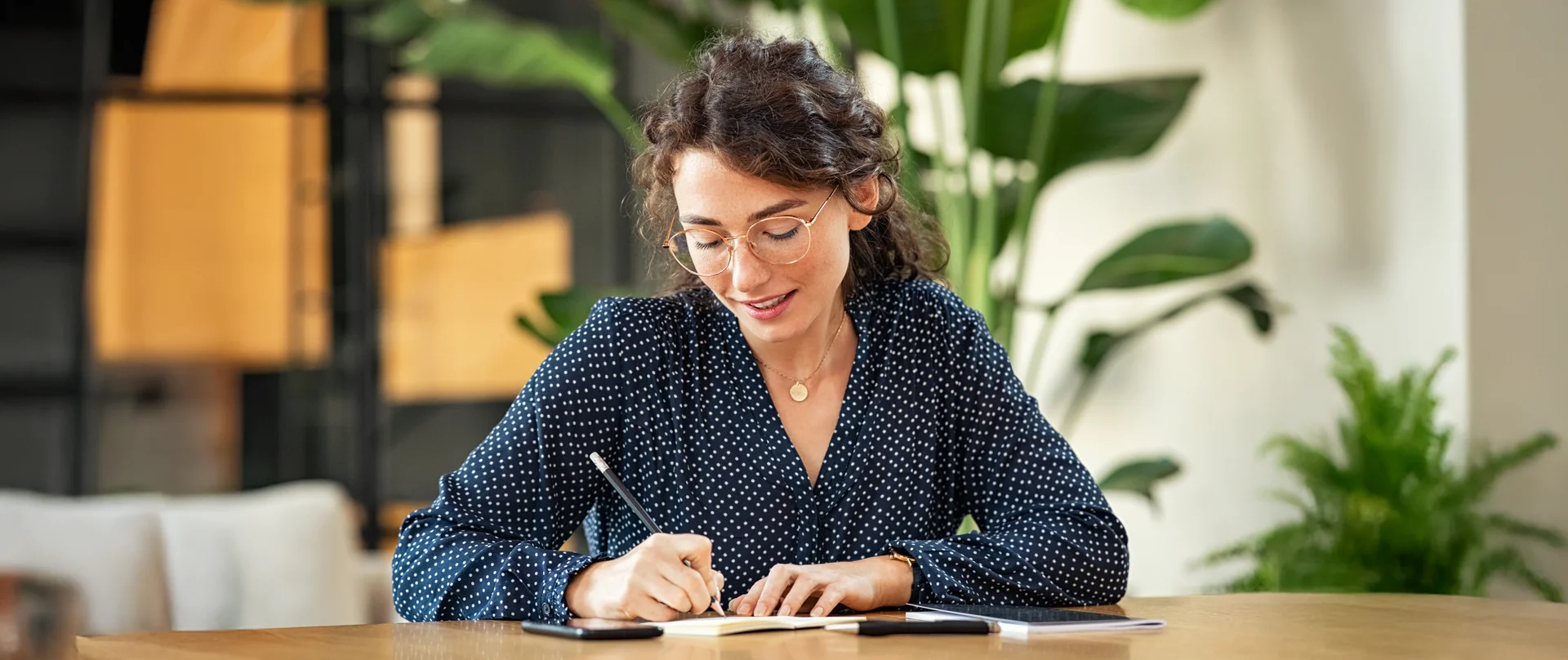 A woman is sitting at a table writing in a notebook