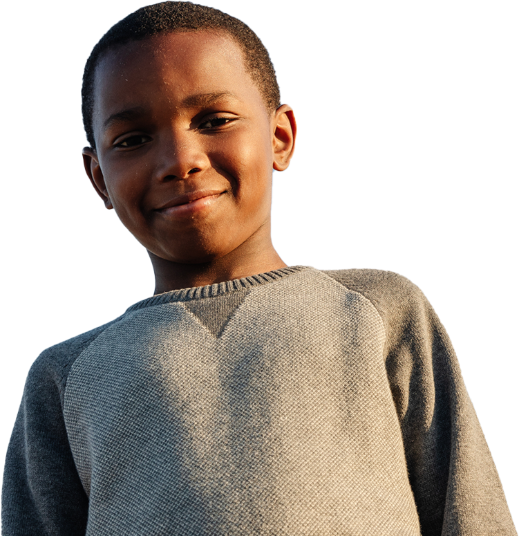 A young boy smiling against a blue sky.