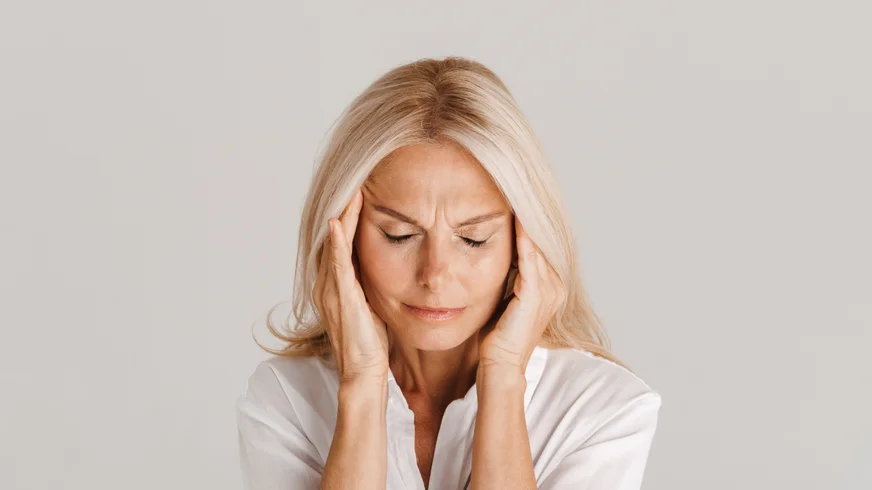 A woman with a headache rubbing her temples.