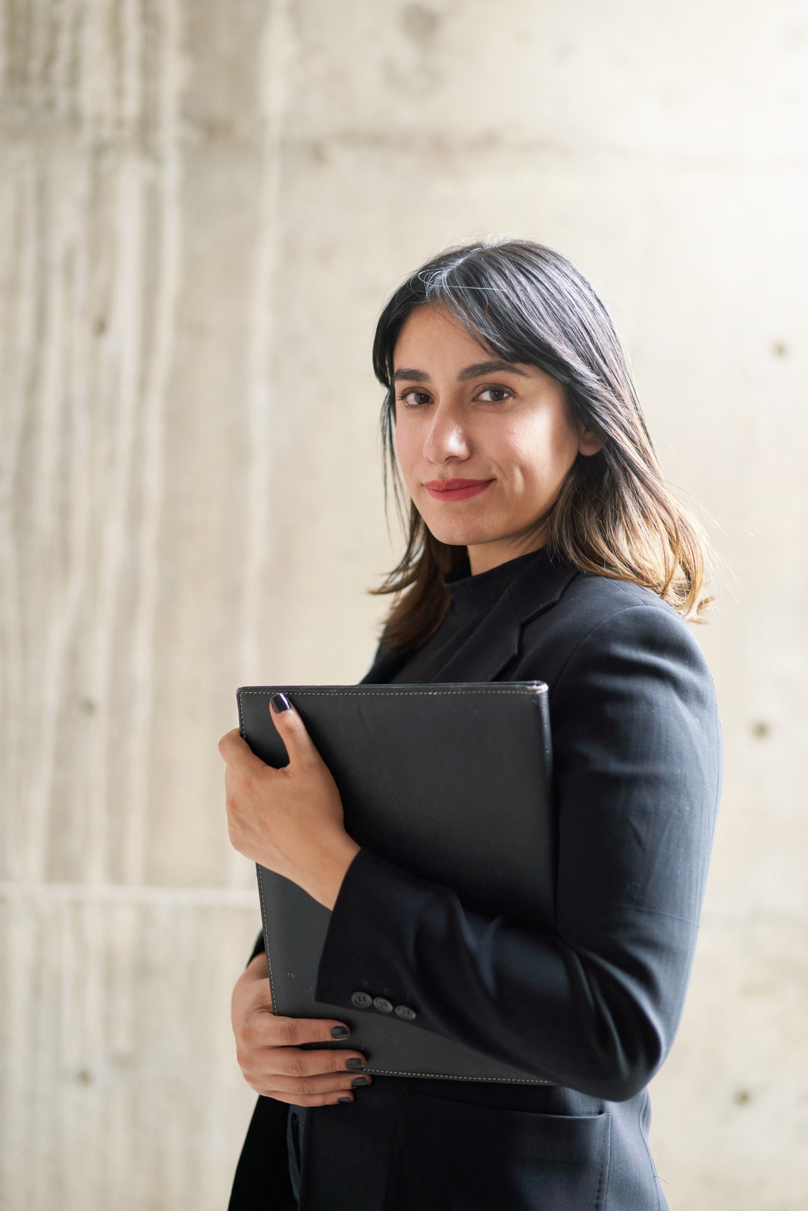 A business woman holding a padfolio.