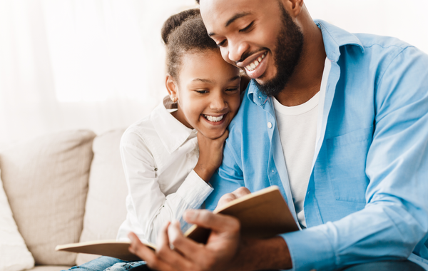 Father and daughter happily reading a book