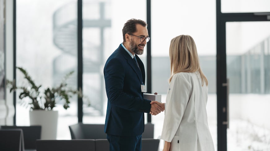 Pharmaceutical sales representative talking with female doctor in medical building. Hospital director consulting with healthcare staff.