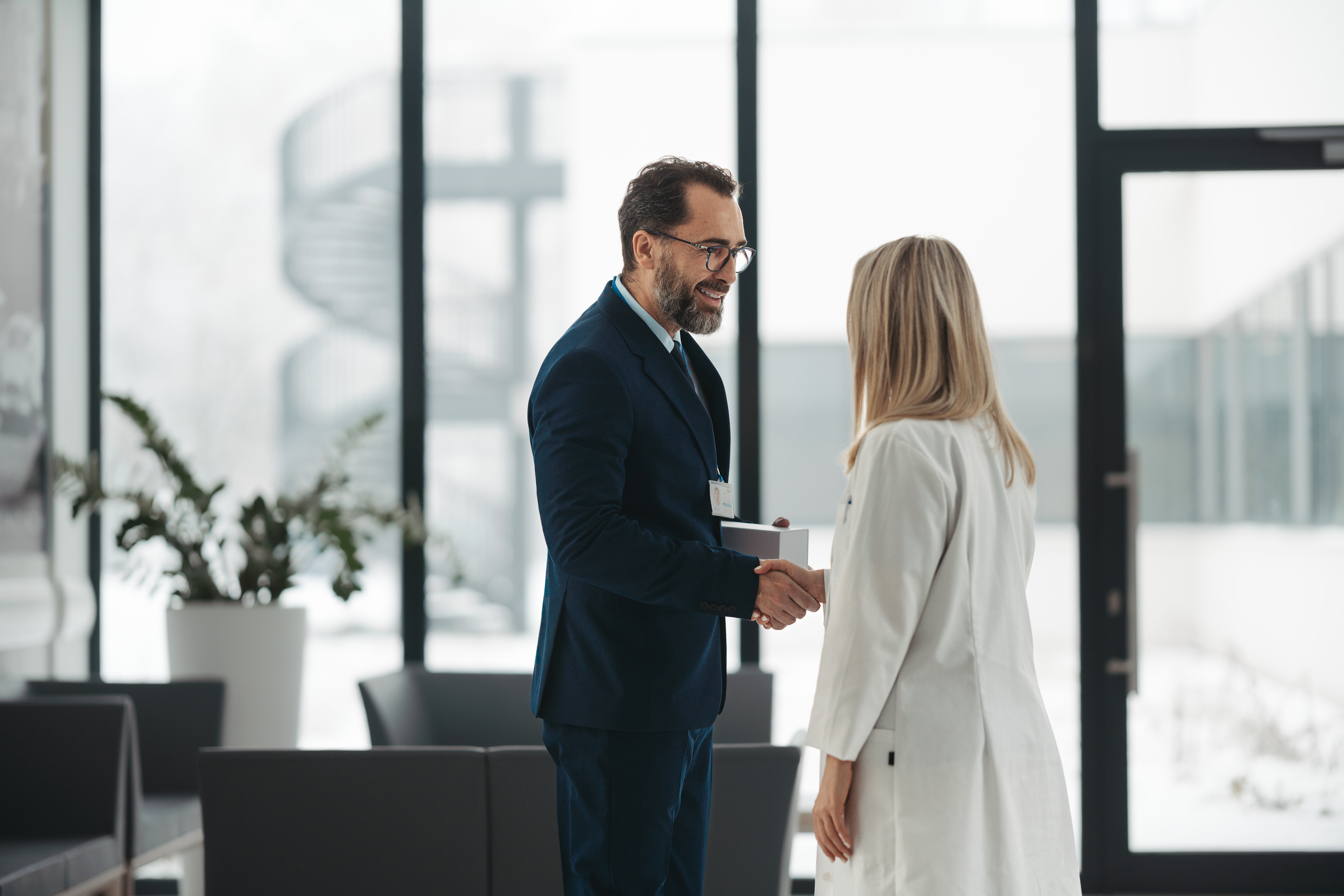 Pharmaceutical sales representative talking with female doctor in medical building. Hospital director consulting with healthcare staff.