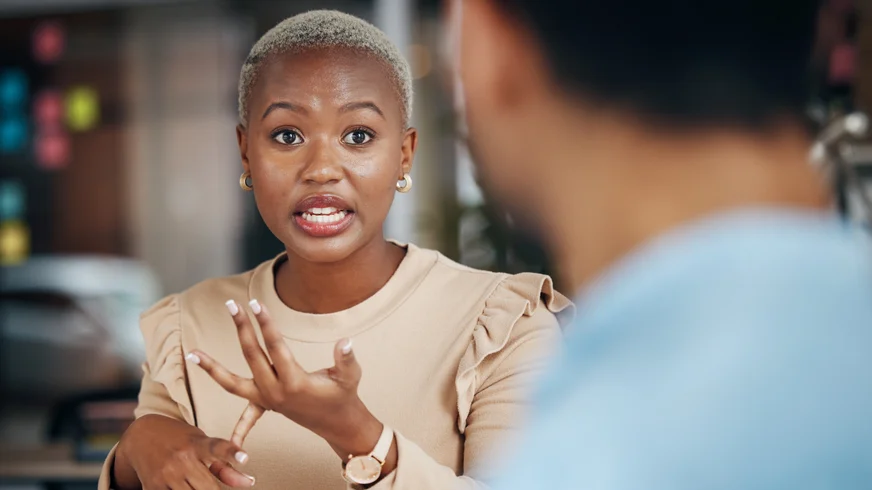 A woman is sitting at a table talking to a man