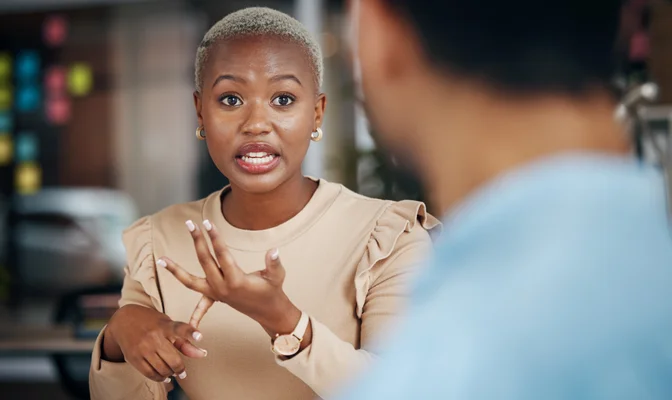 A woman is sitting at a table talking to a man