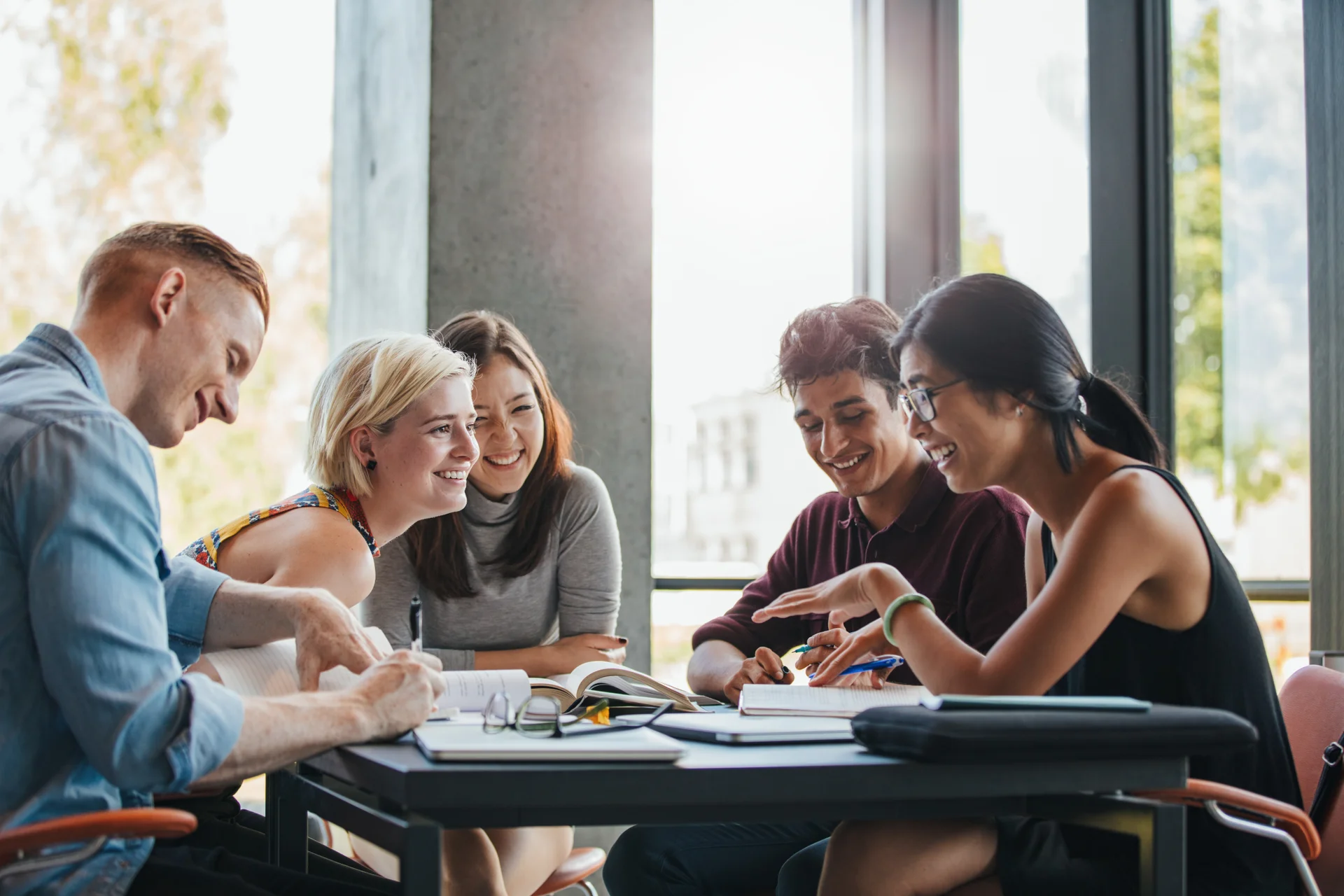 A group of people are sitting around a table with books