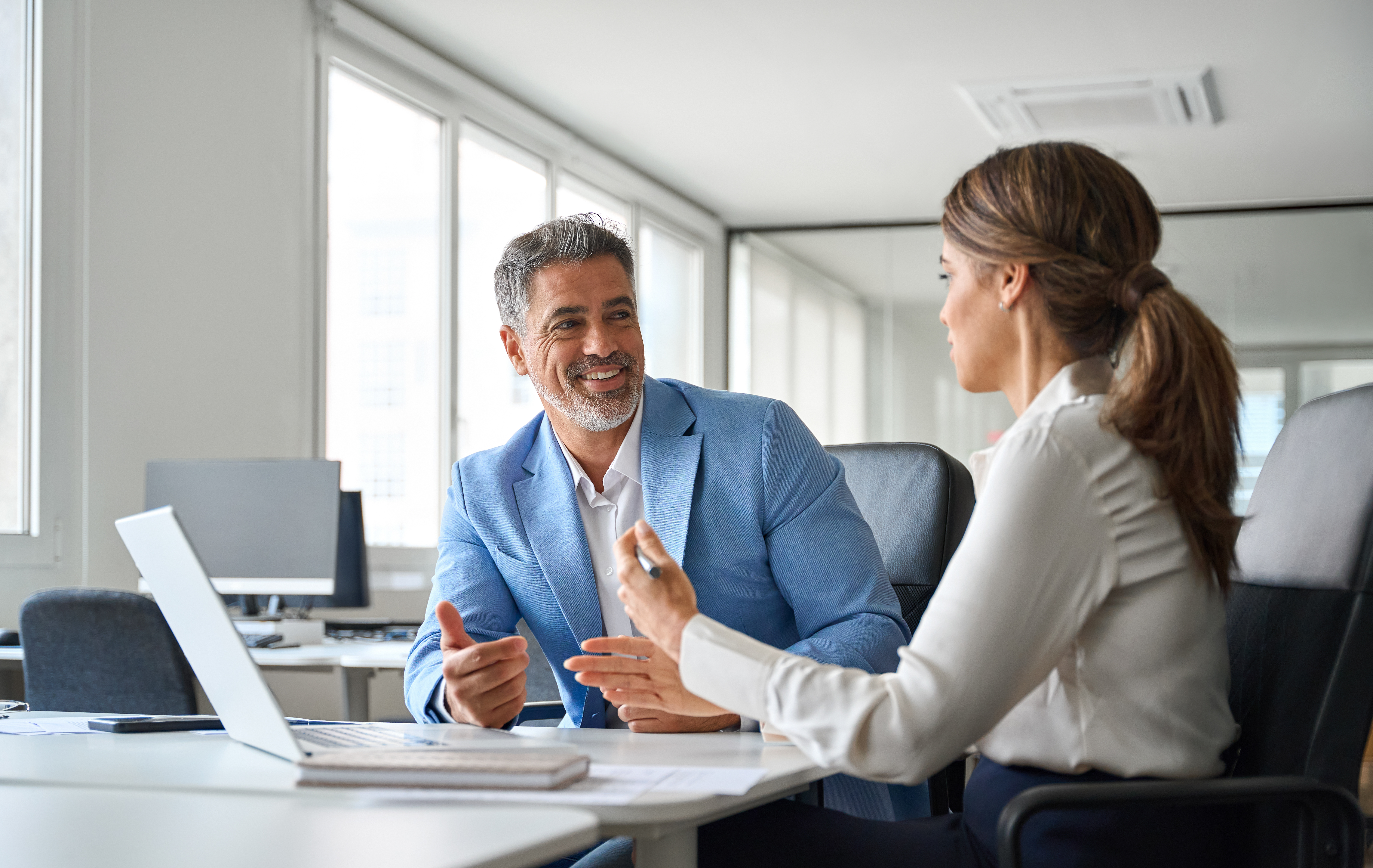 A man and a woman are sitting at a table talking to each other