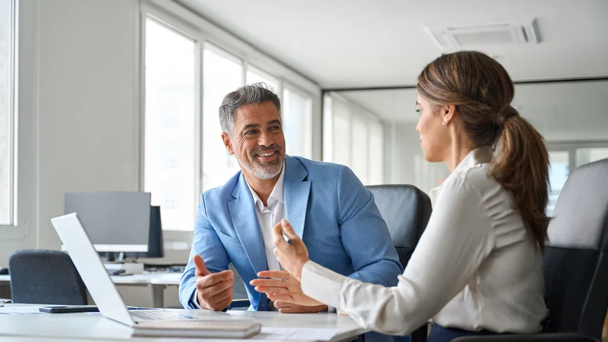 A man and a woman are sitting at a table talking to each other
