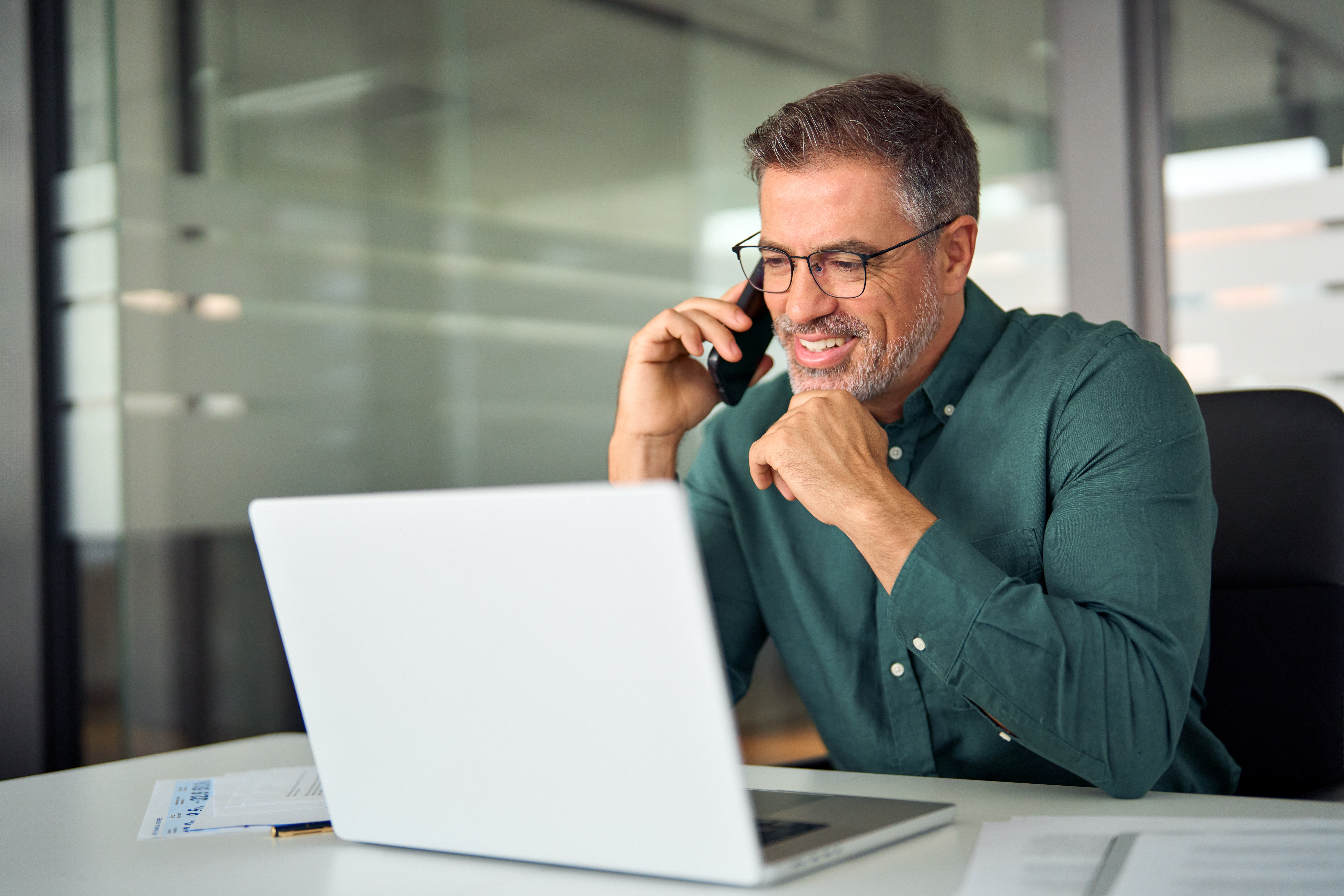 A man on a phone call while working on his laptop
