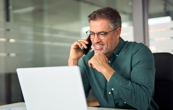 A man on a phone call while working on his laptop