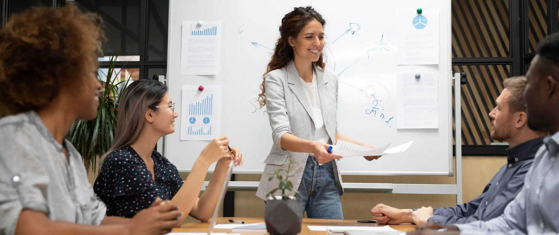 A woman is giving a presentation to a group of people sitting around a table