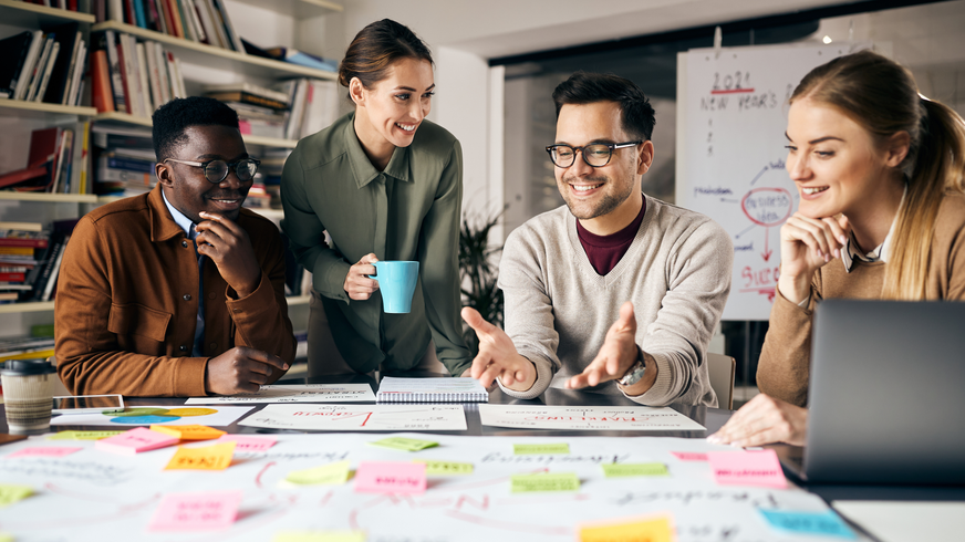 A group of people are sitting around a table with sticky notes on it
