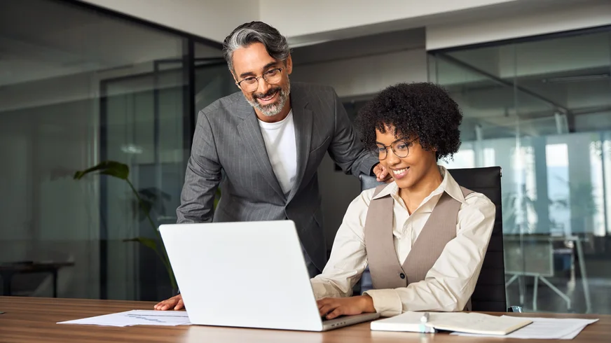 A man and a woman are looking at a laptop computer