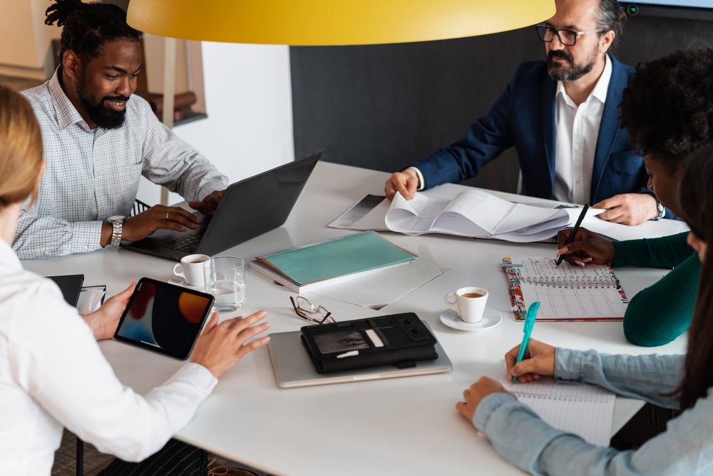 A group of people are sitting around a table having a meeting.