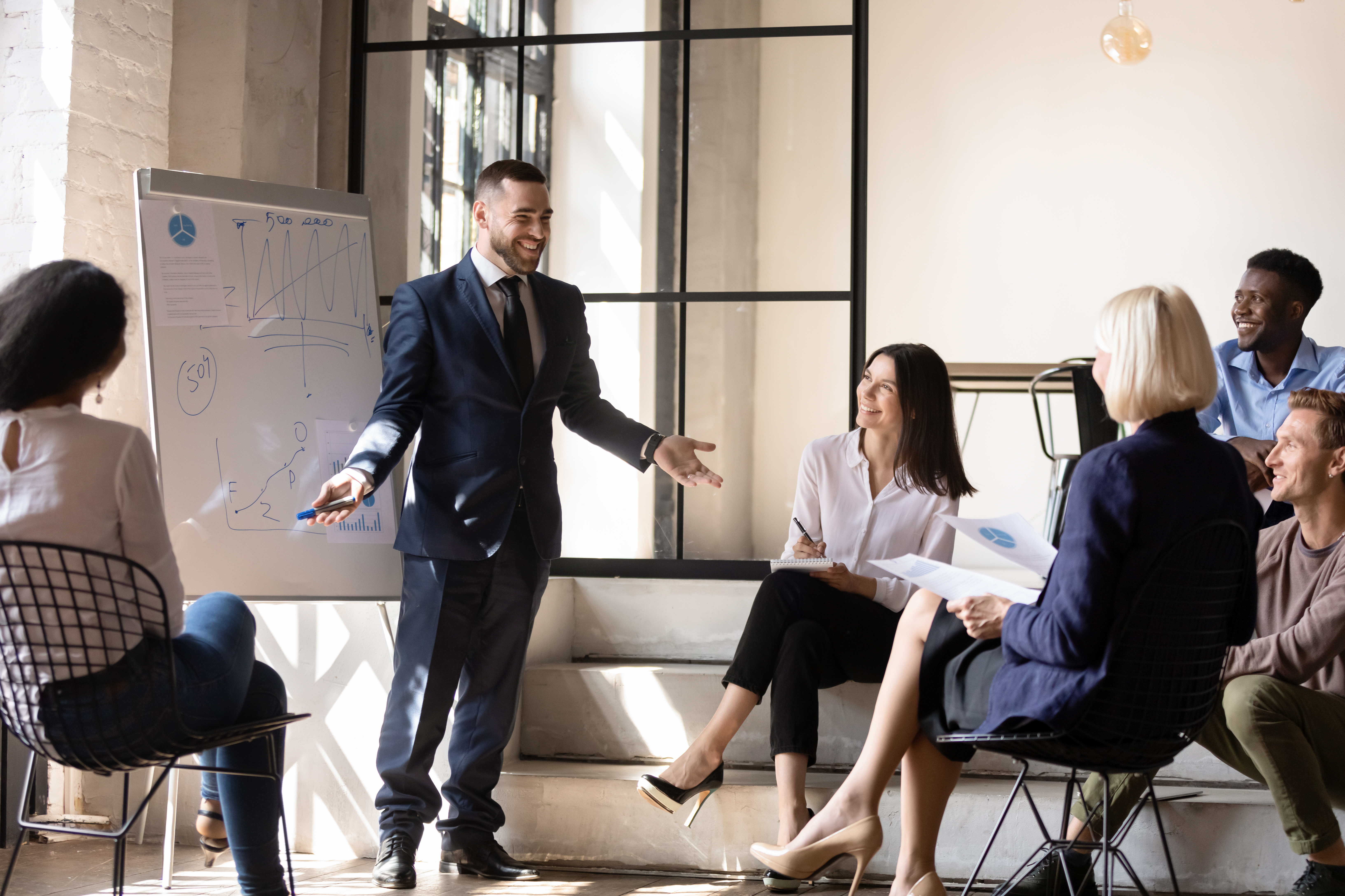 A man in a suit is giving a presentation to a group of people
