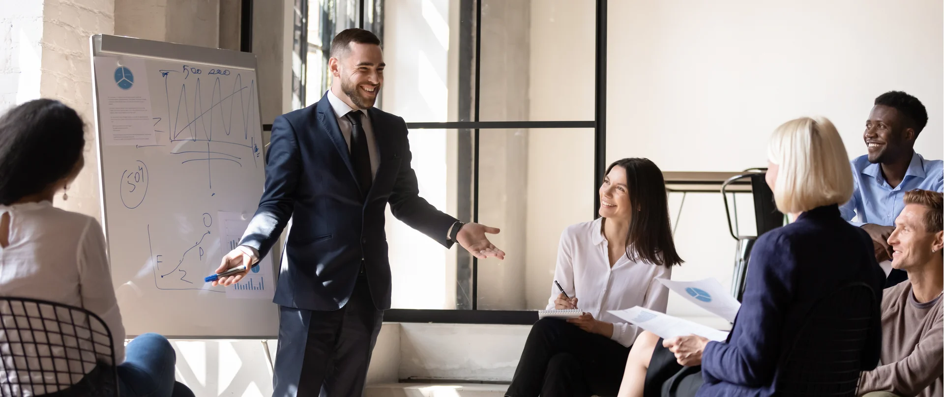 A man in a suit is giving a presentation to a group of people