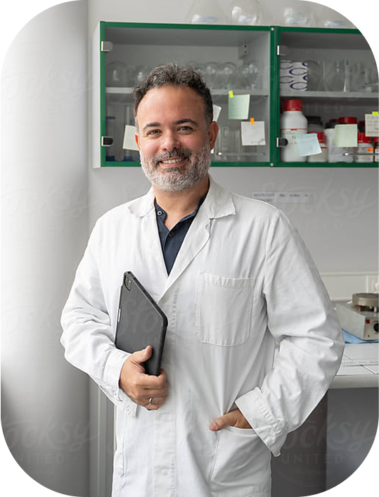 A scientist smiling while standing in a lab.