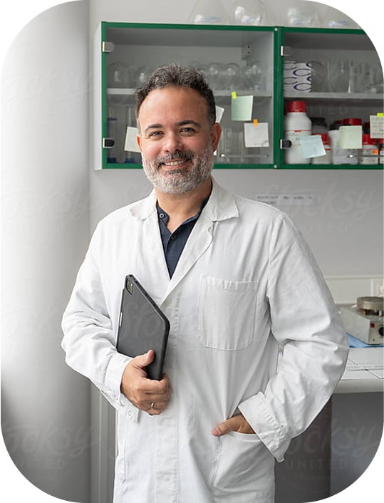 A scientist smiling while standing in a lab.