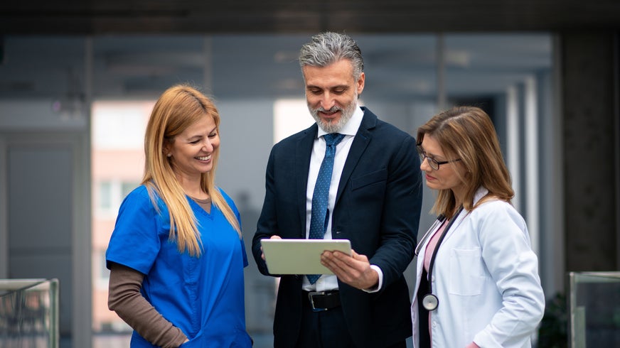 Doctors talking to pharmaceutical sales representative, presenting new pharmaceutical product.