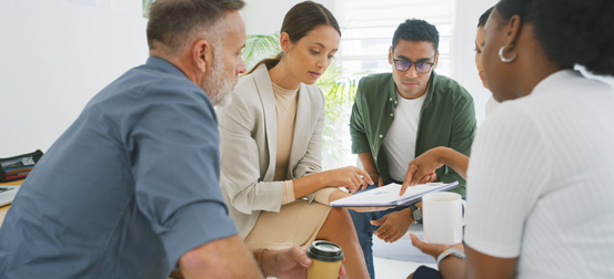 A group of people are sitting around a table having a meeting
