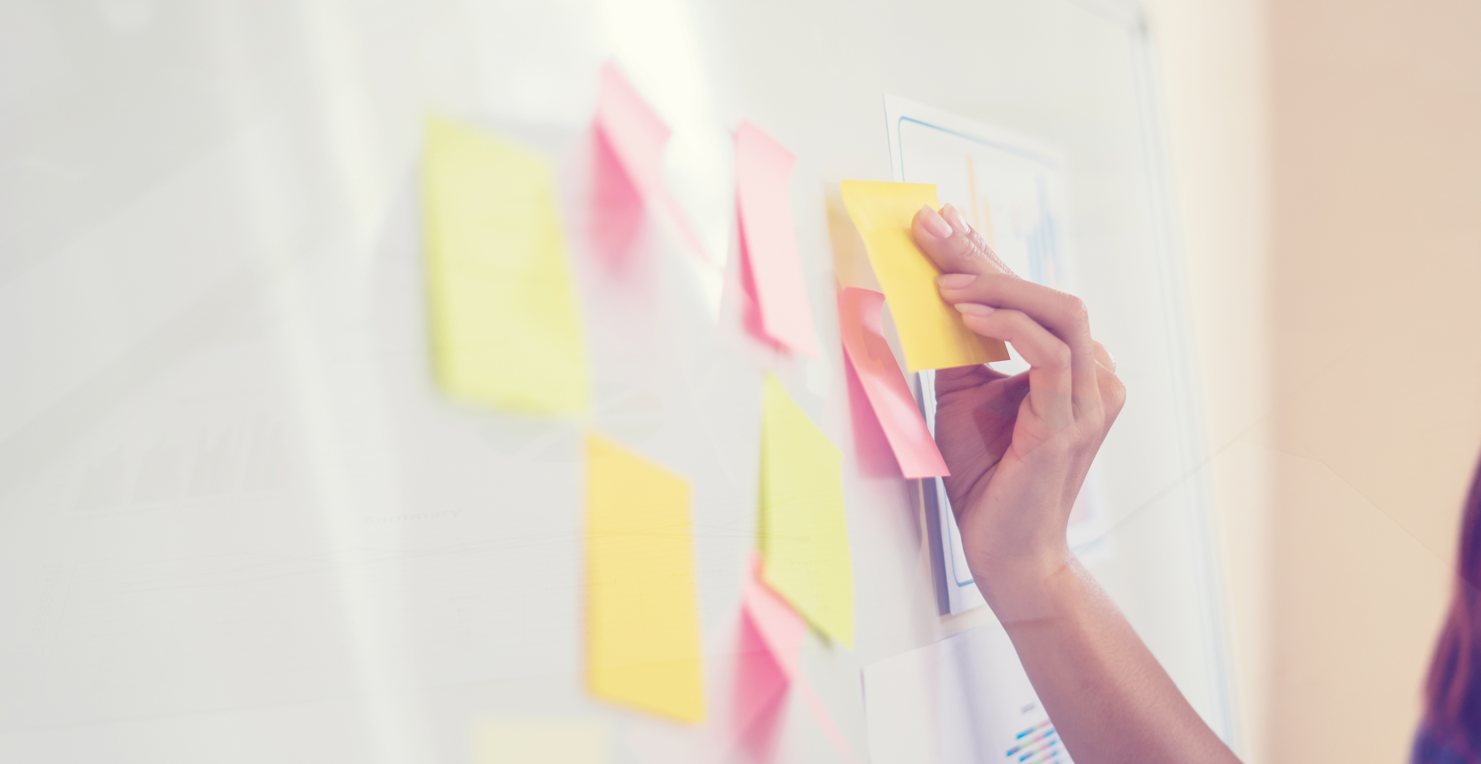 A woman is writing on a whiteboard with sticky notes