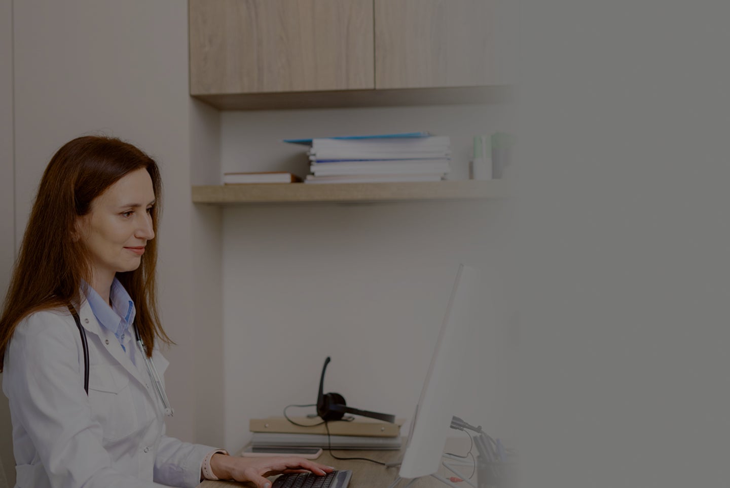 A doctor working on a computer at a desk.