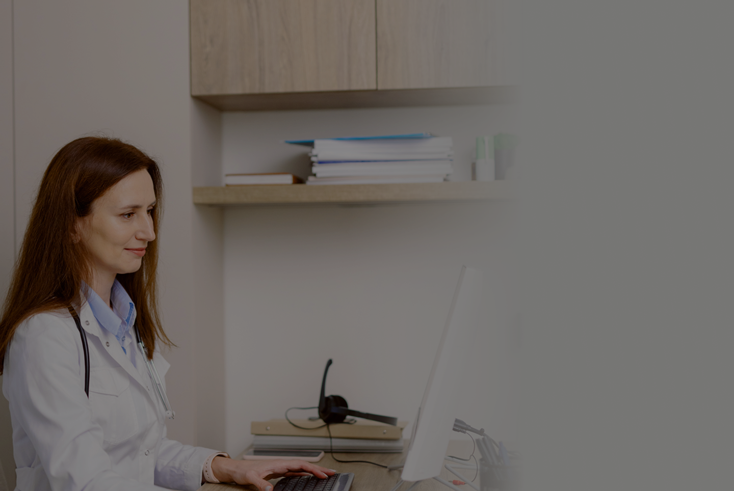 A doctor working on a computer at a desk.