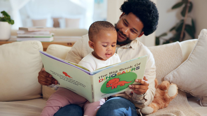 A father and child bonding over "the big book of dinosaurs."