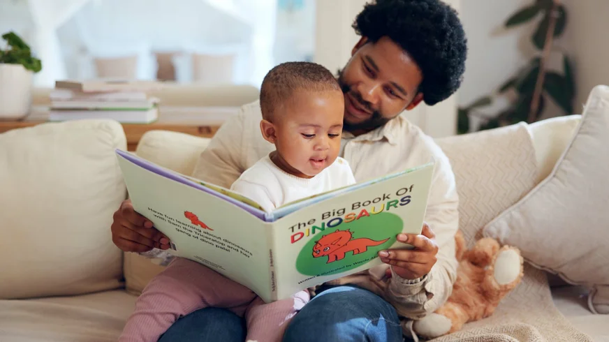 A father and child bonding over "the big book of dinosaurs."
