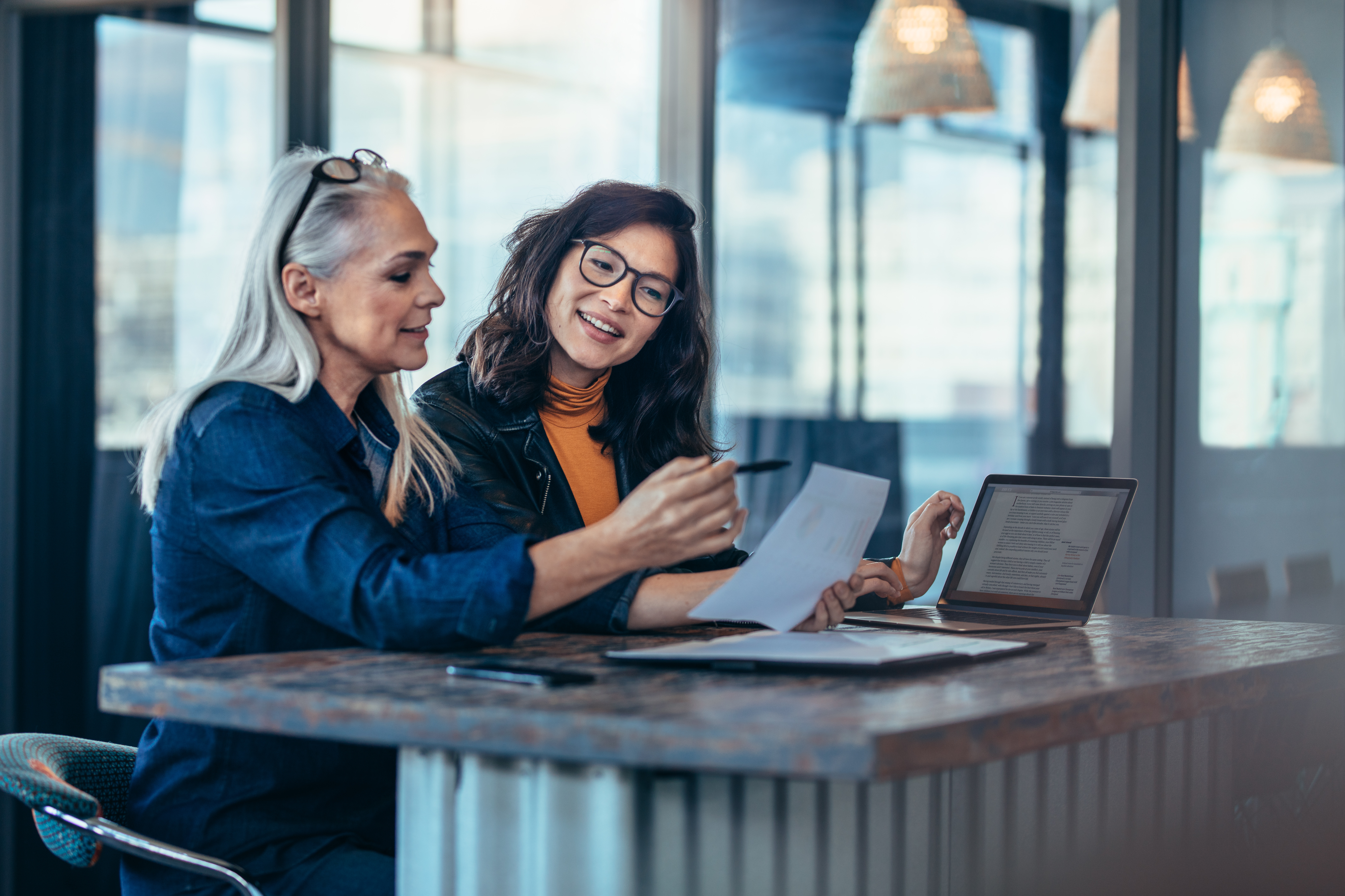 Two women are sitting at a table looking at a piece of paper
