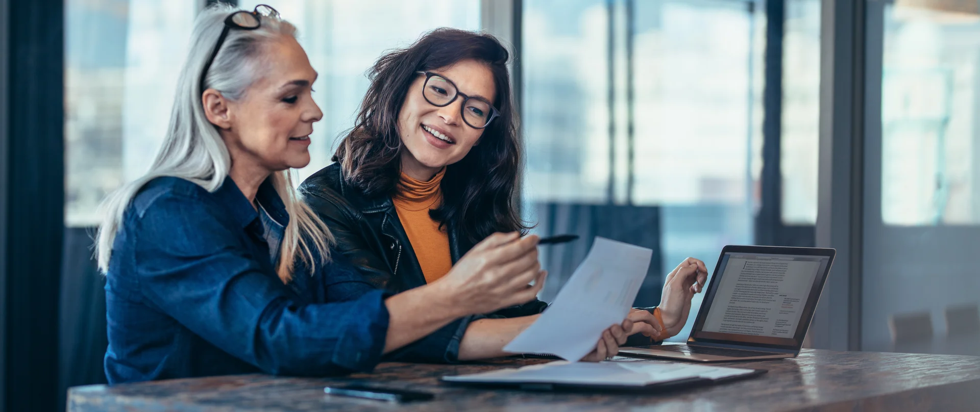 Two women are sitting at a table looking at a piece of paper