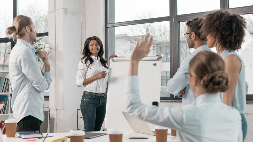 A woman is raising her hand to answer a question during a meeting
