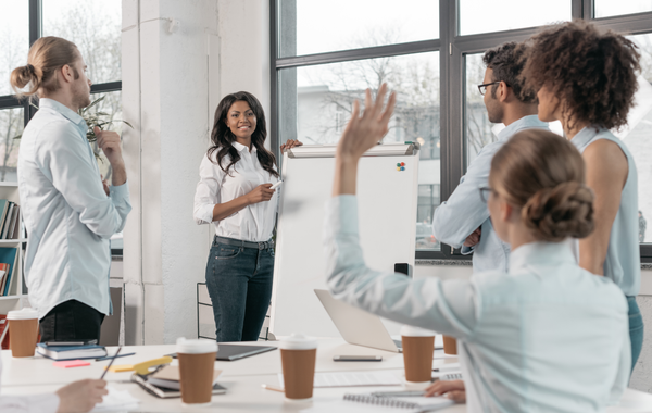 A woman is raising her hand to answer a question during a meeting