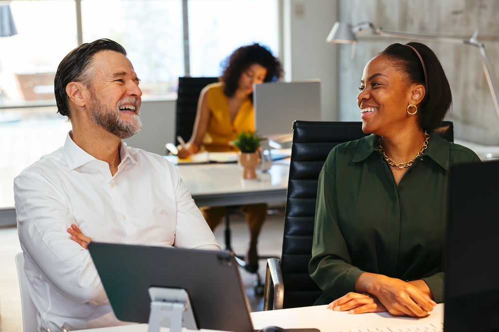 Colleagues talking and smiling in the office.