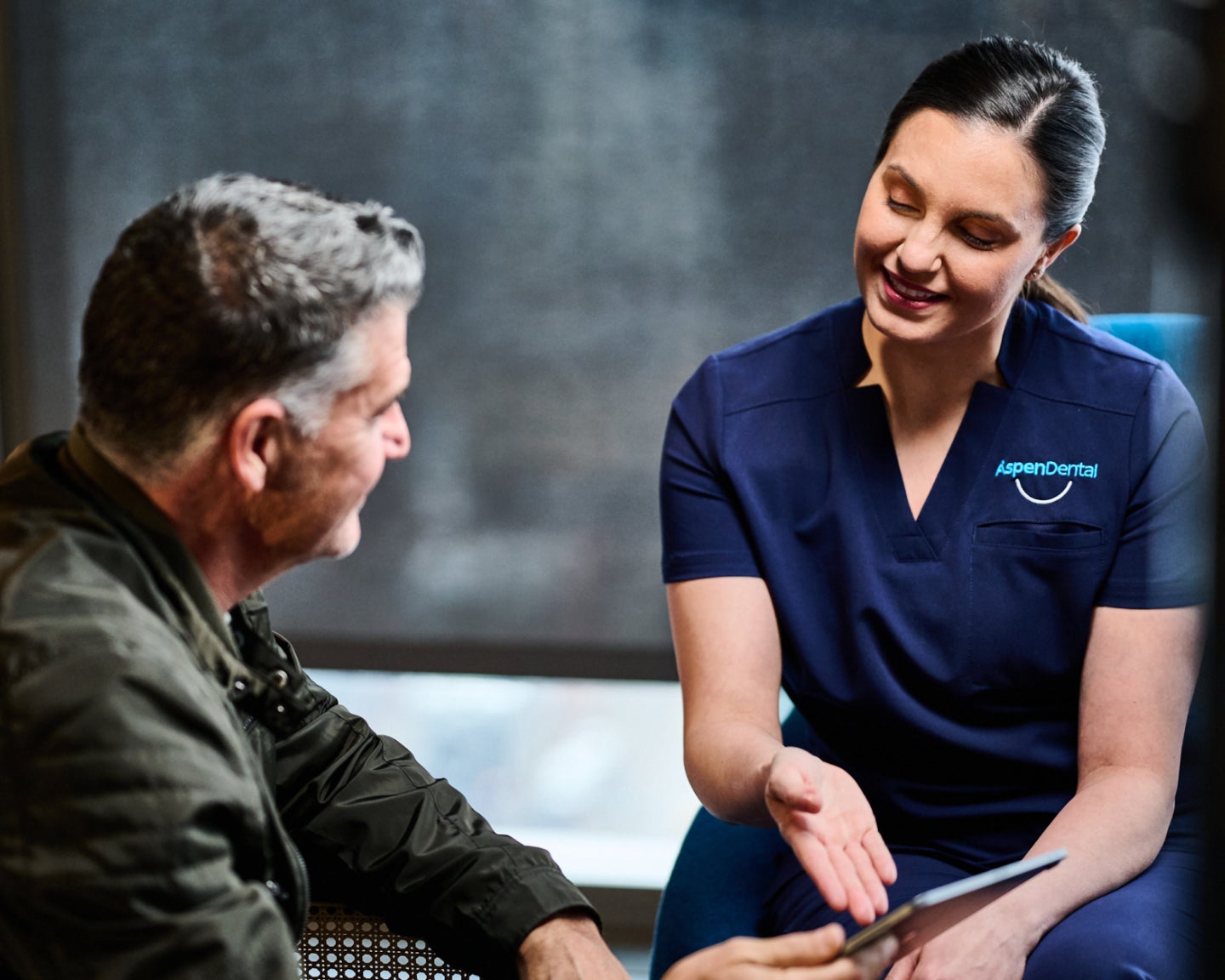 Aspen Dental professional consulting with a patient, discussing dental treatment options including titanium implants, in a bright and welcoming clinic setting.