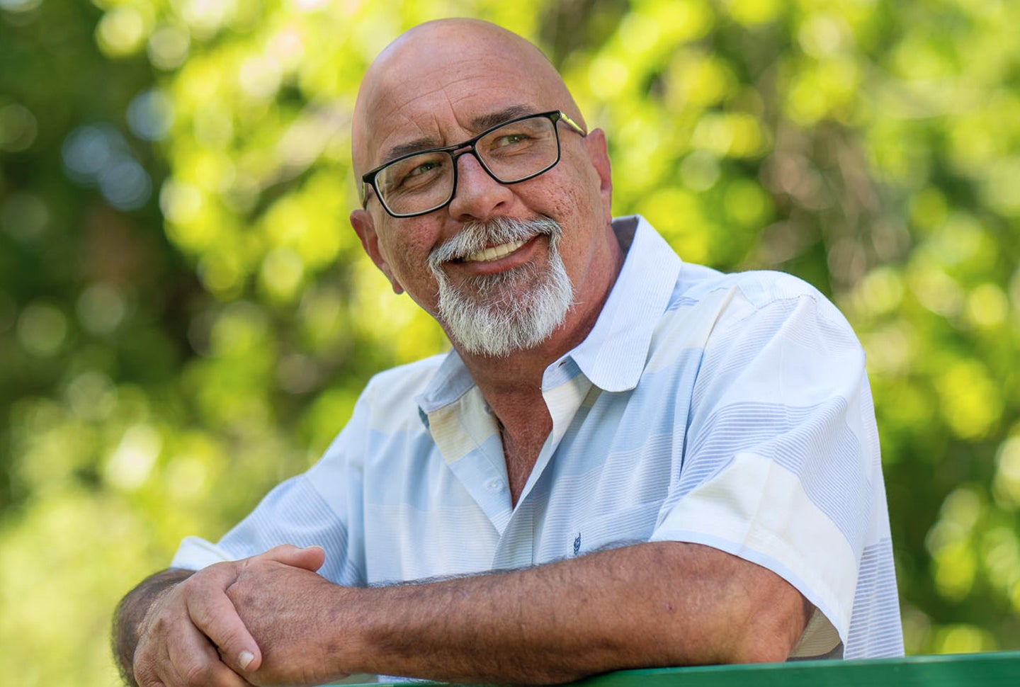 A smiling older man with glasses and a white shirt sits outside. He shows why ClearChoice is the best choice for dental implants. The focus is on changing smiles for good.