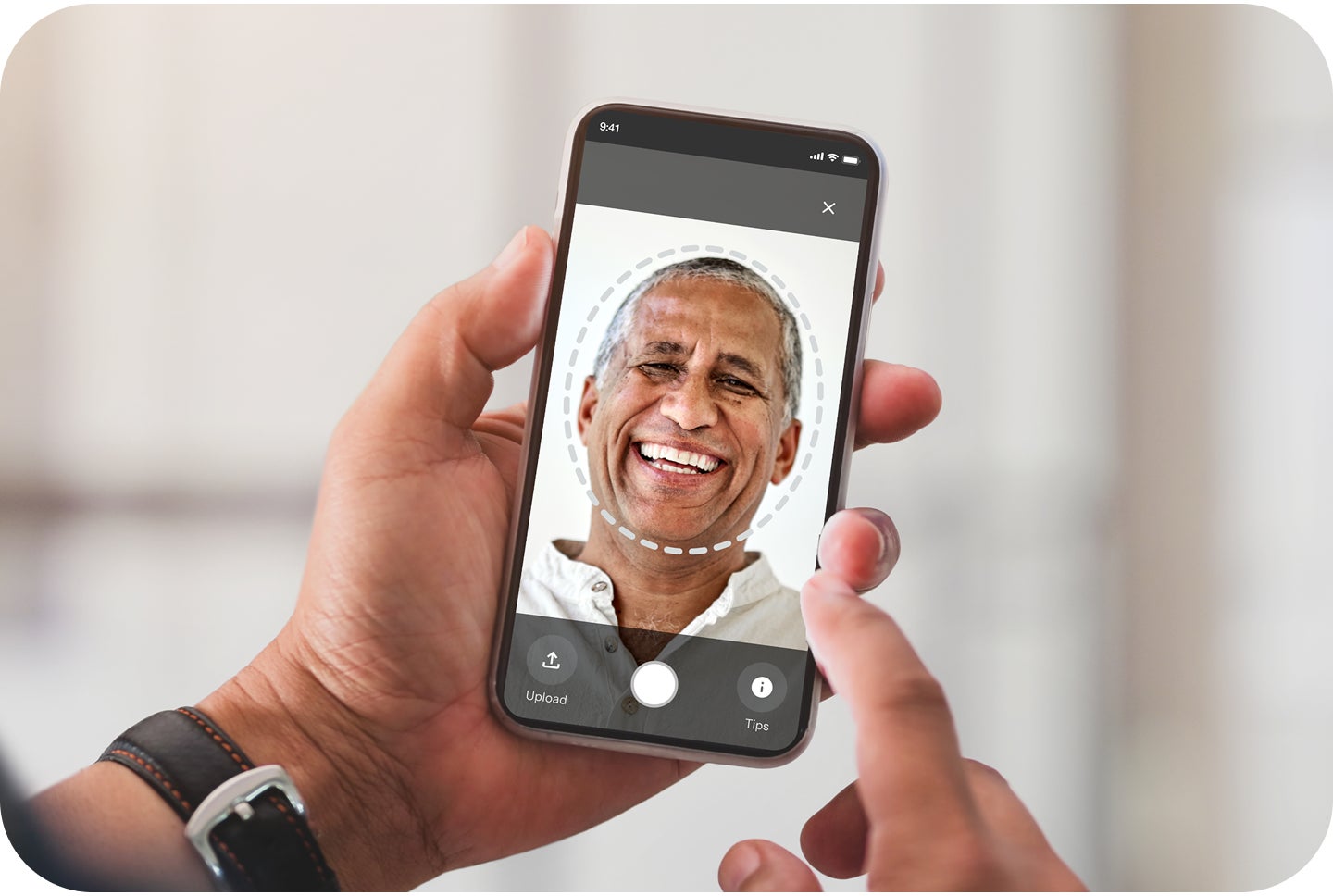 A patient holds a smartphone to take a selfie of themselves to use within Aspen Dental's smile try-on mobile simulator tool to see what their smile could look like with dental care services and treatment.