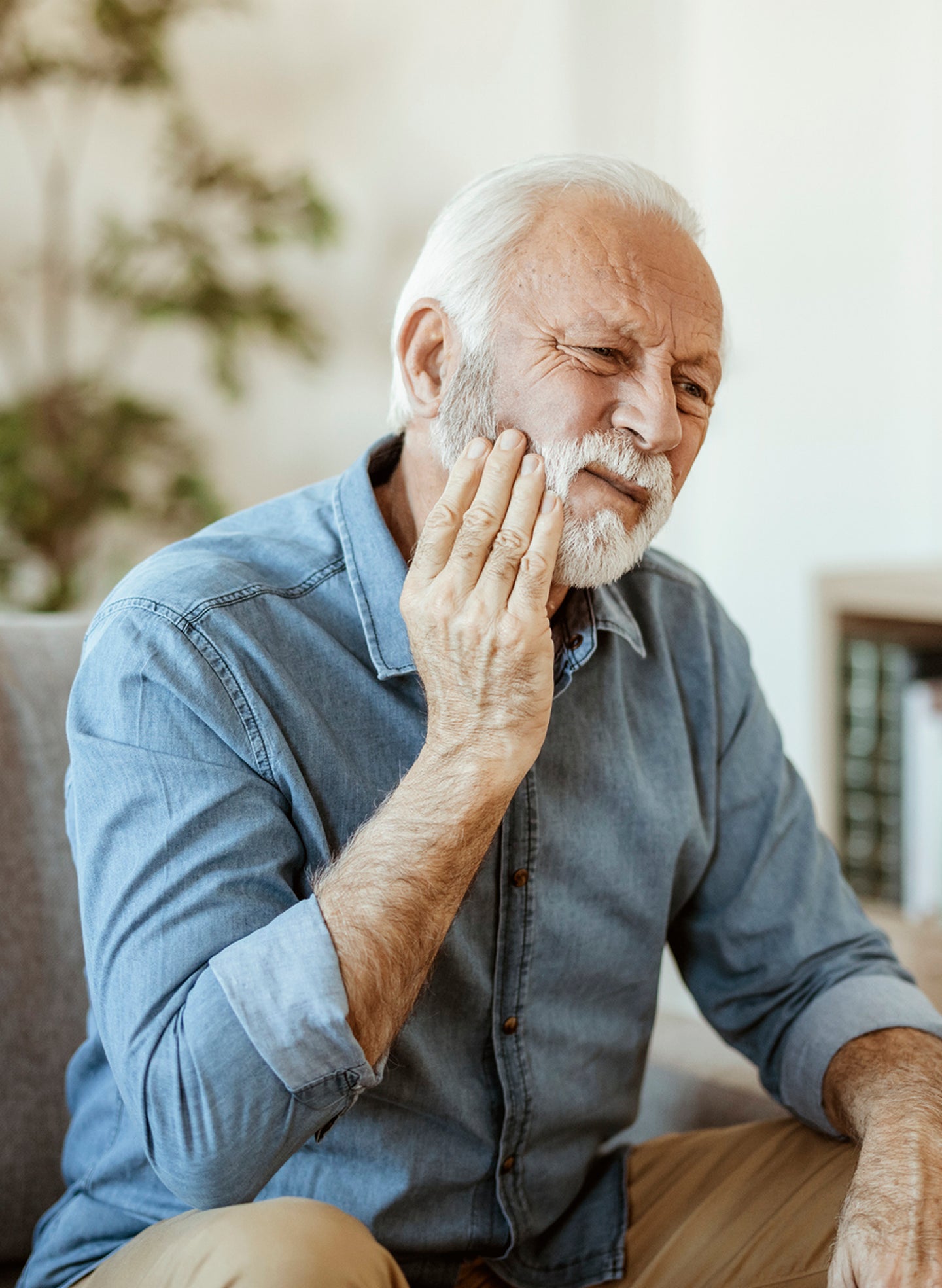 An older man holds his jaw in discomfort, a possible sign of sinus-related tooth pain affecting the upper molars.