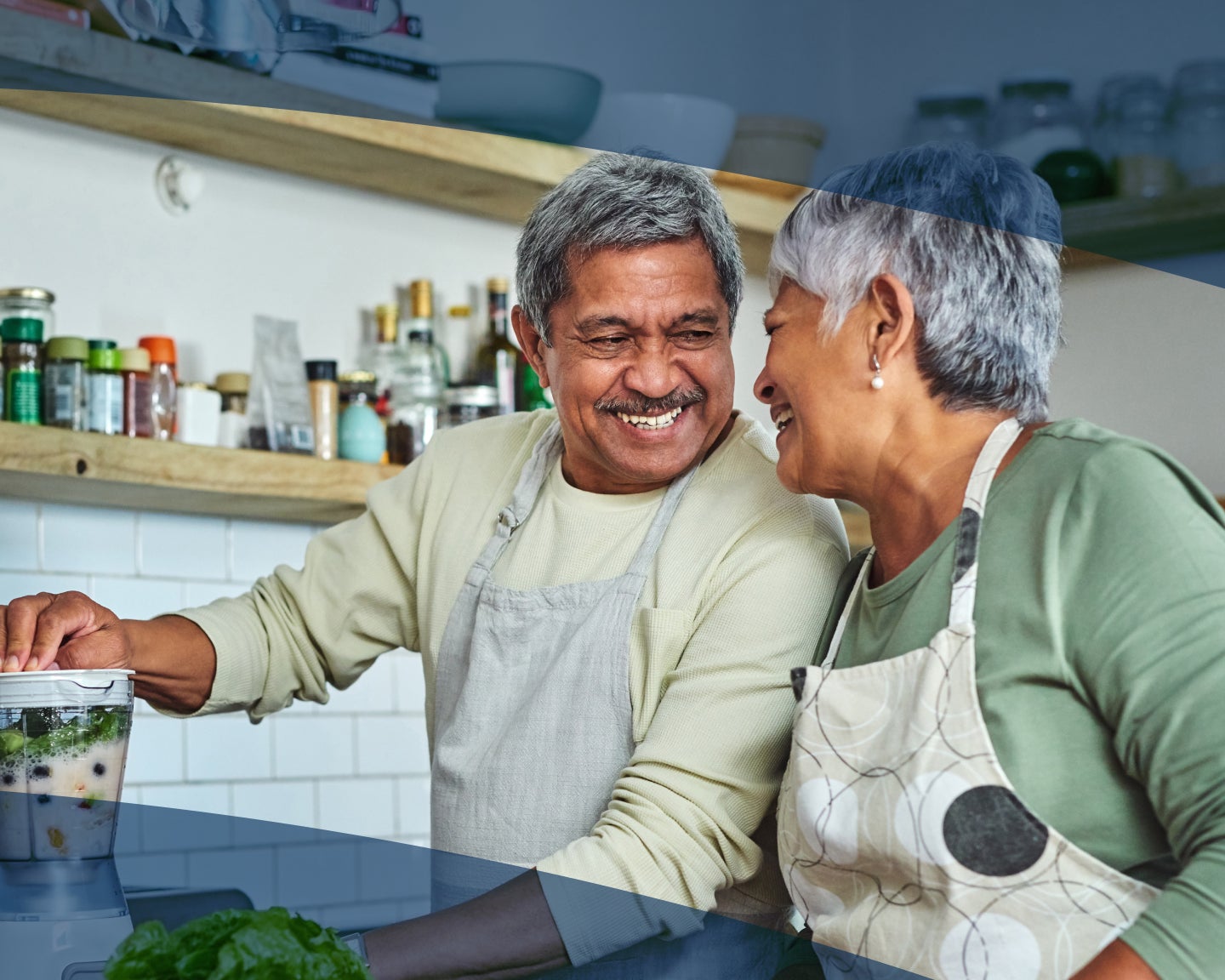 A man and woman are smiling while preparing food in a kitchen