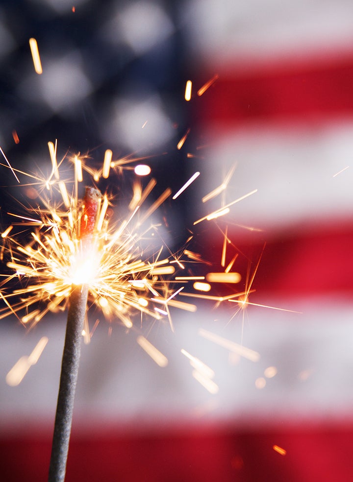 A close up of a sparkler in front of an american flag