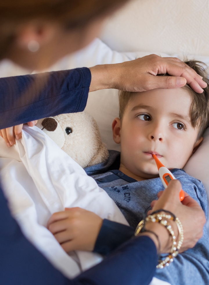 A woman is taking a child 's temperature with a thermometer