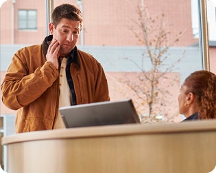 A man in a brown jacket is talking on a cell phone