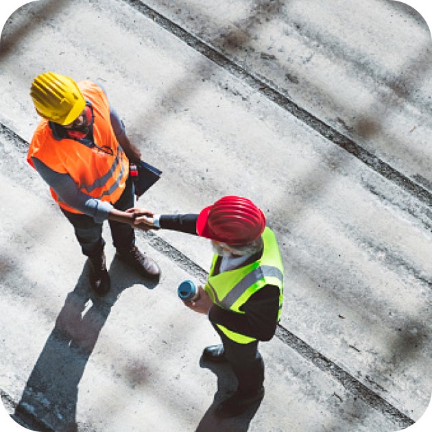 An overhead shot of two construction workers shaking hands.